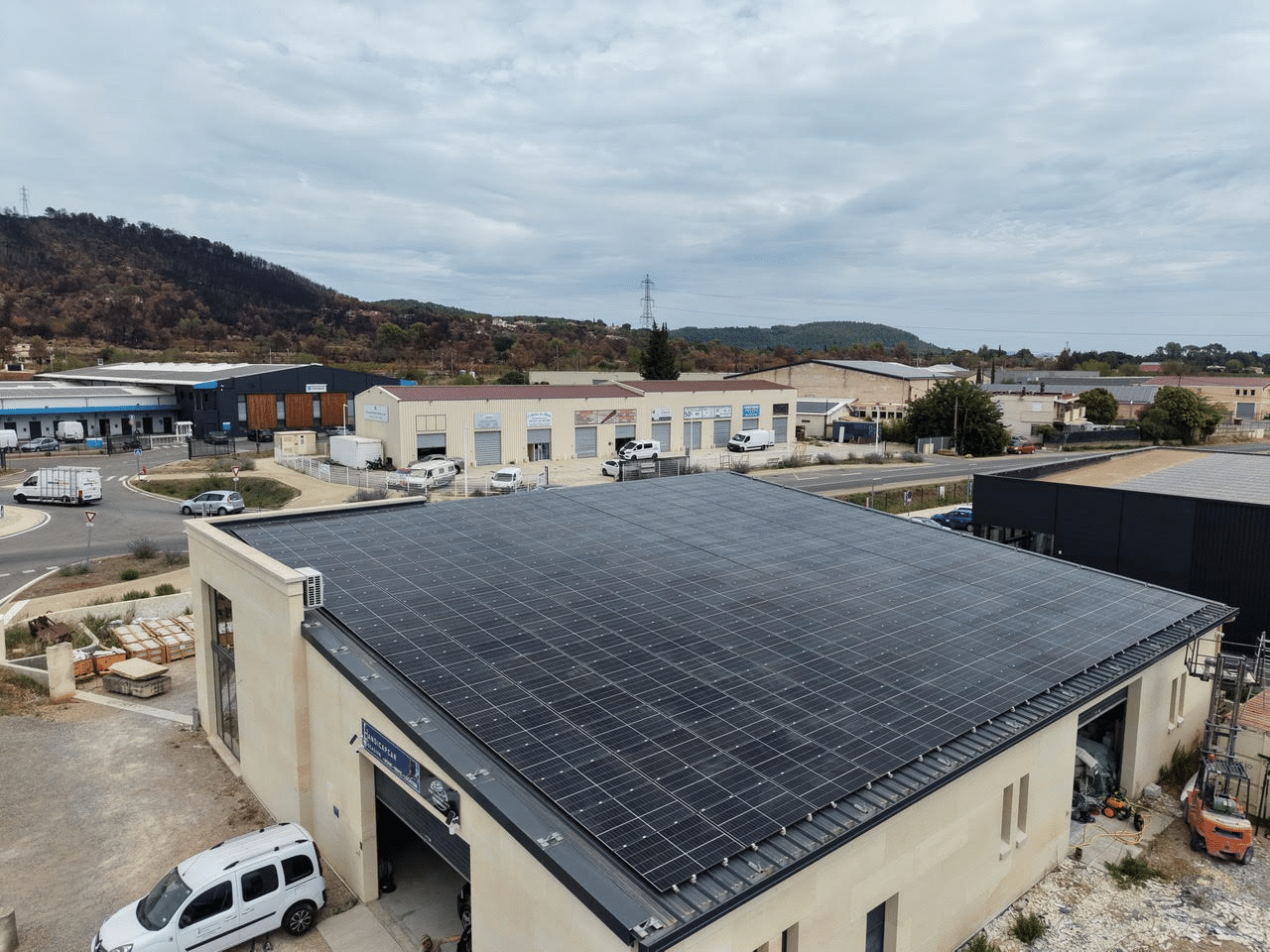Panneaux photovoltaïques sur la toiture d'un bâtiment commercial en zone d'activités, nettoyés par drone