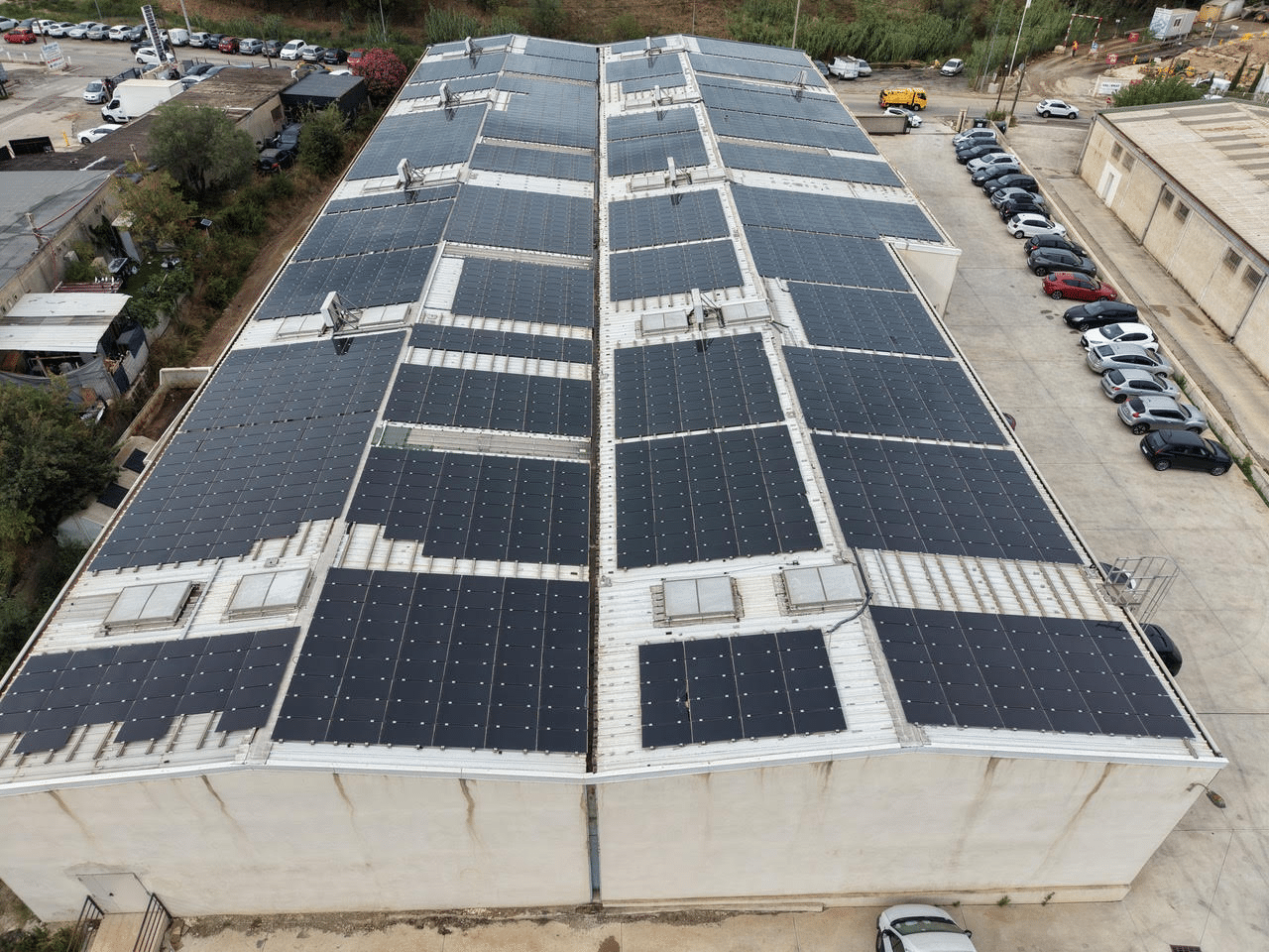 Vue aérienne d'une grande centrale photovoltaïque sur toiture d'un bâtiment industriel, nettoyée par drone dans le Var