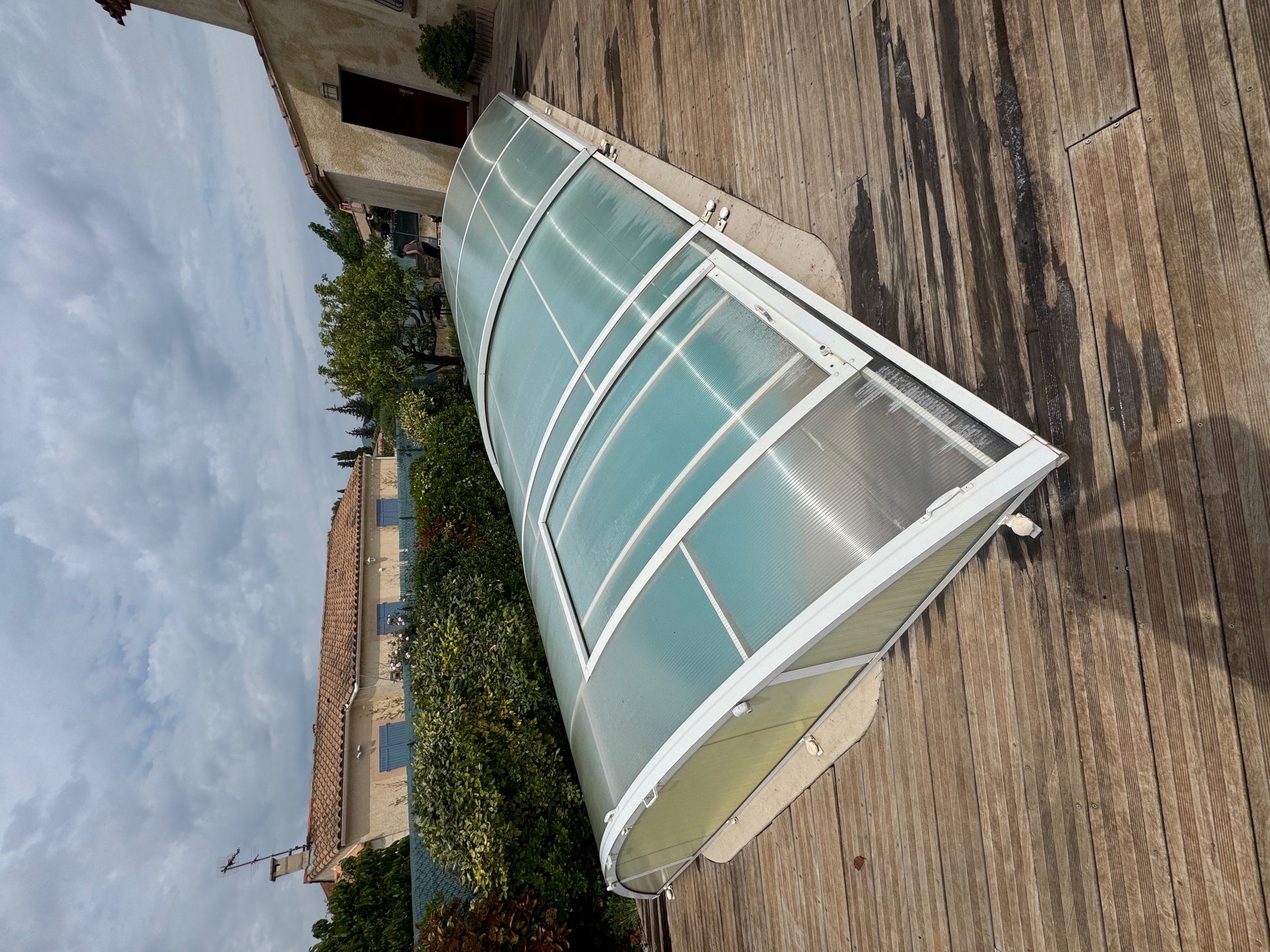 Abri de piscine en polycarbonate nettoyé sur une terrasse en bois