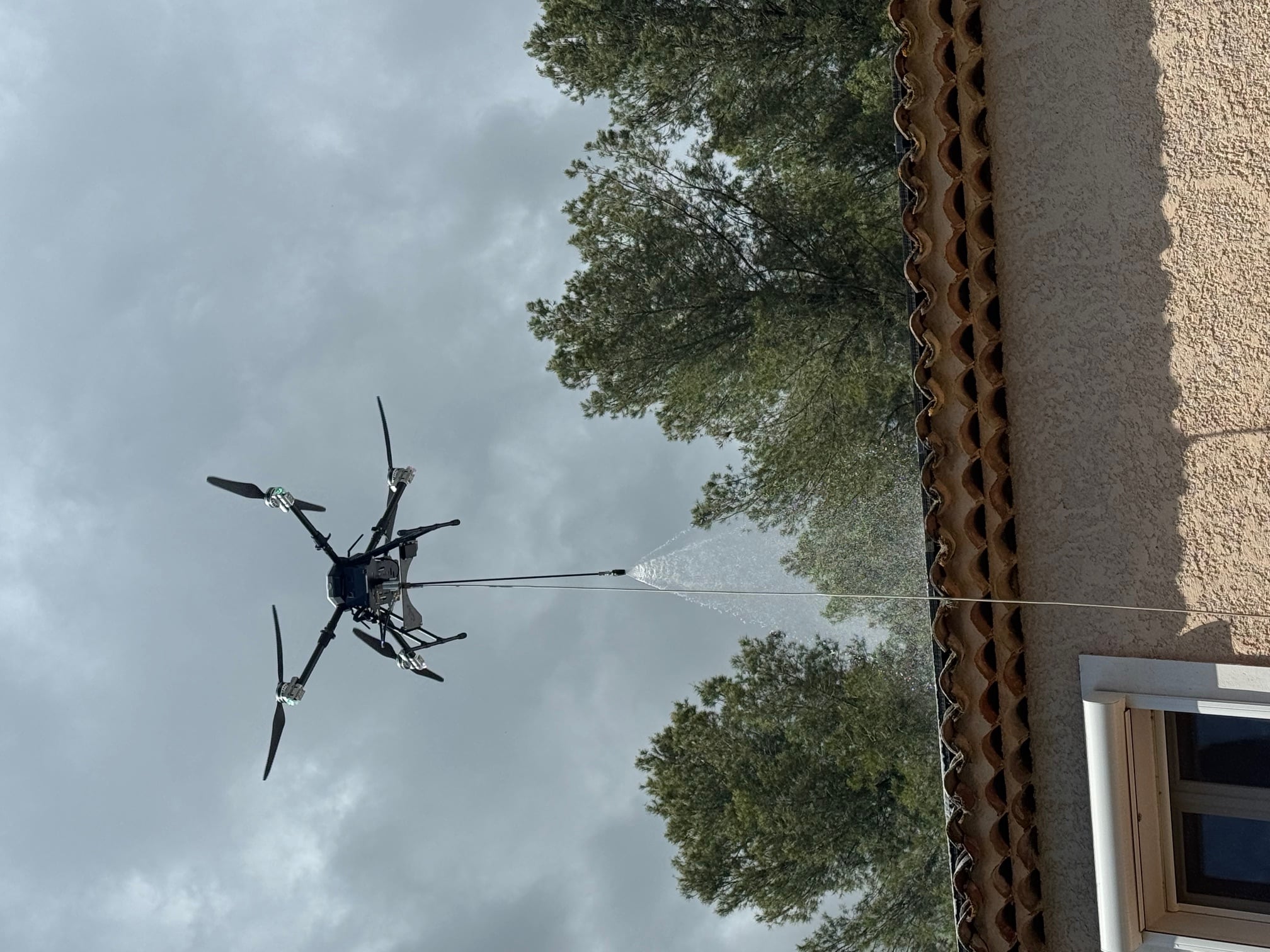 Drone Aerodronecleaner pulvérisant de l'eau pour nettoyer une toiture