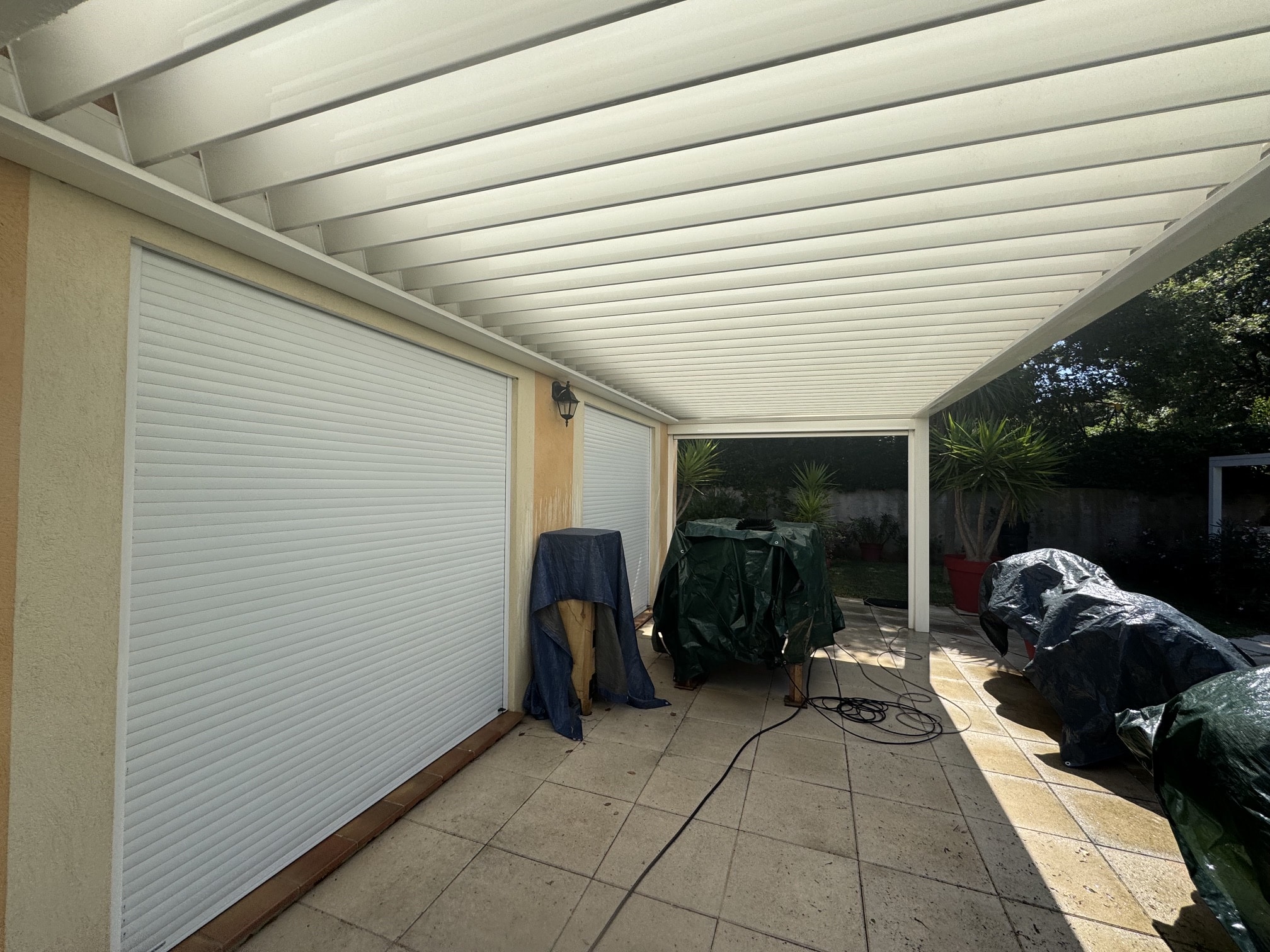 Pergola à lames blanches nettoyée au-dessus d'une terrasse carrelée