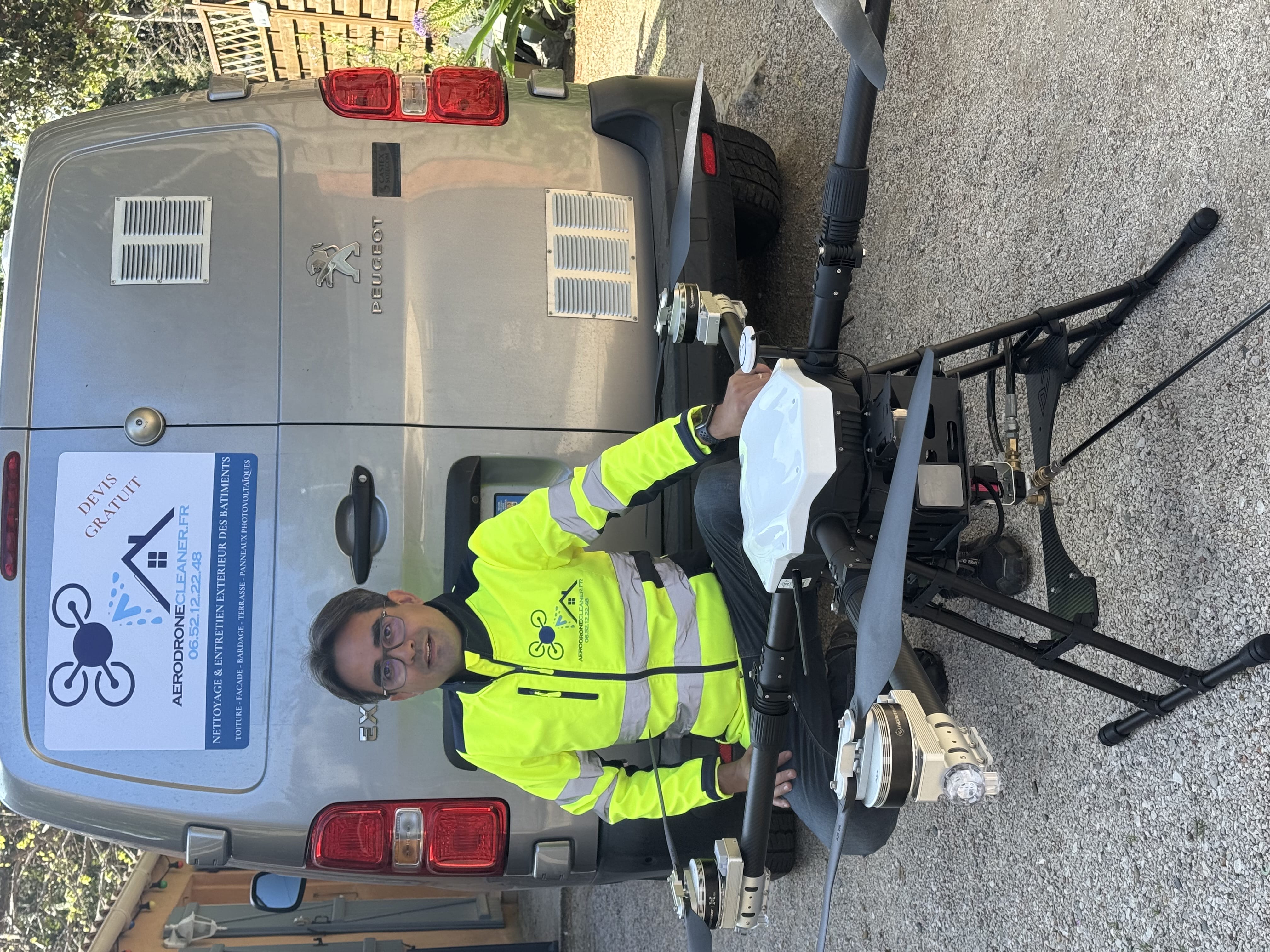 Professionnel Aerodronecleaner en tenue haute visibilité tenant son drone devant le camion de l'entreprise